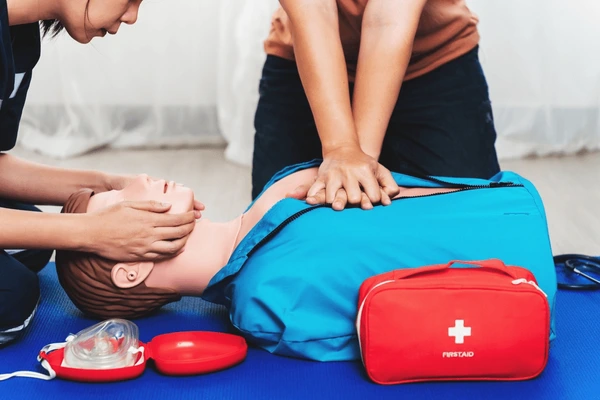 Two people practice CPR on a test dummy